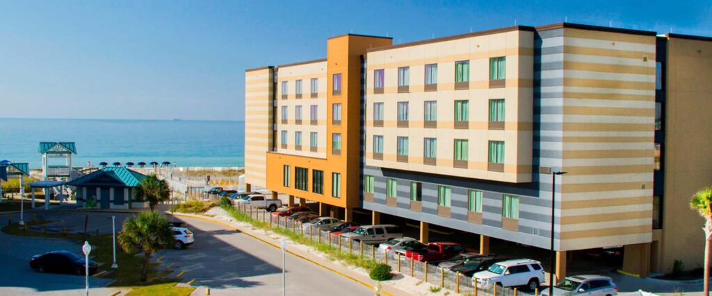 Modern Wavecrest Lodge with striped exterior, parked cars, and ocean views in the background.