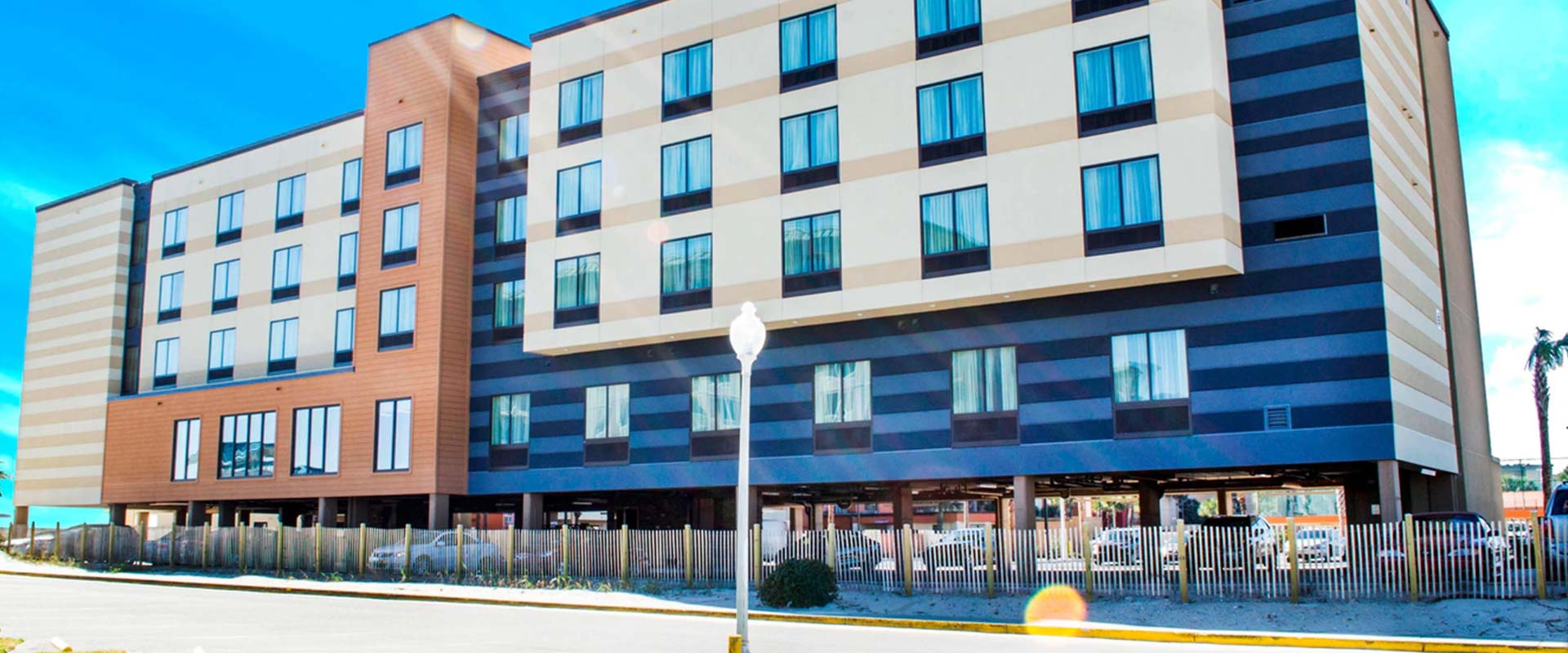 Four-story Fort Walton Beach hotel with striped facade, large windows, and parking underneath.