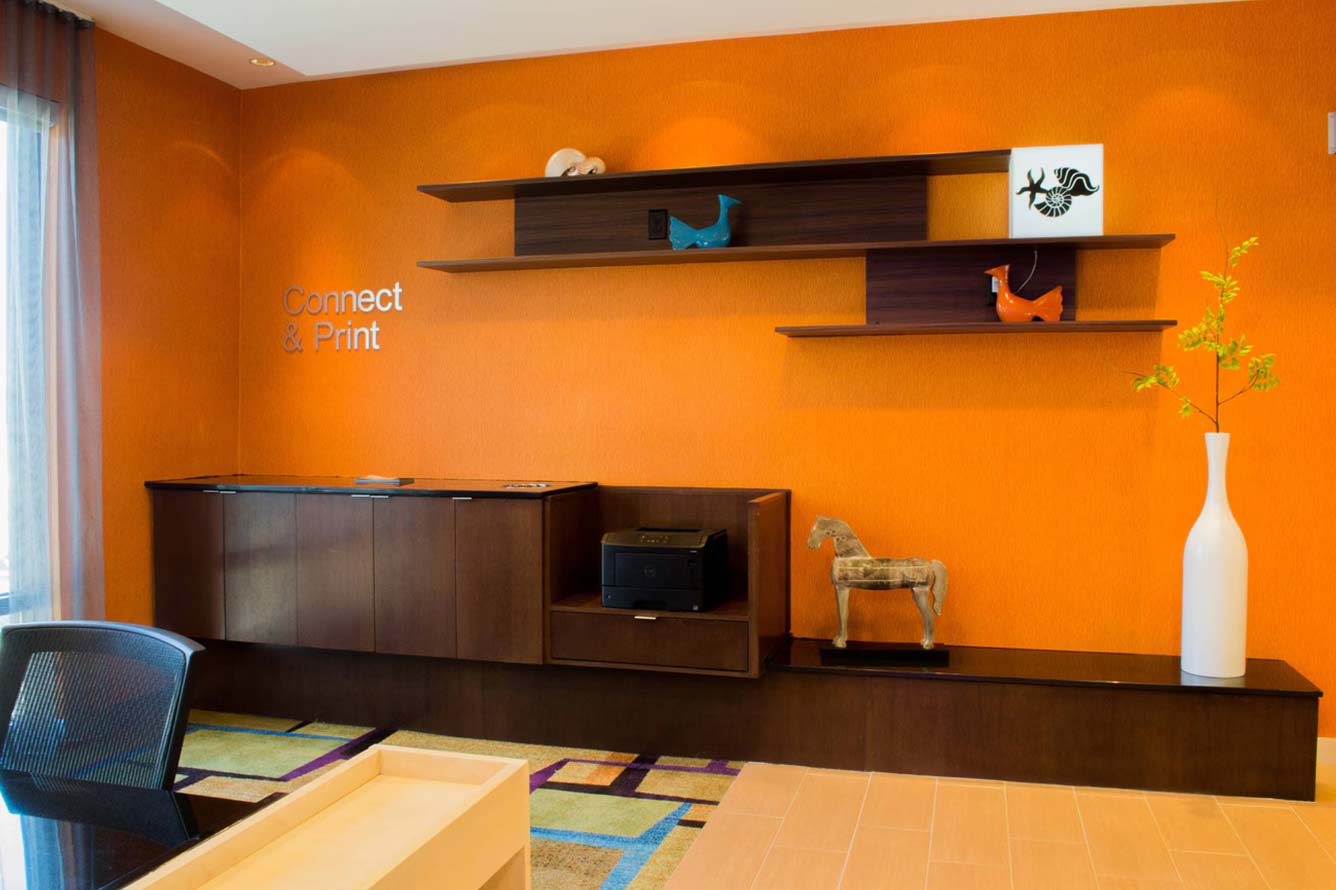 Modern office corner with orange wall, shelves, a printer—perfect for a Fort Walton Beach hotel.