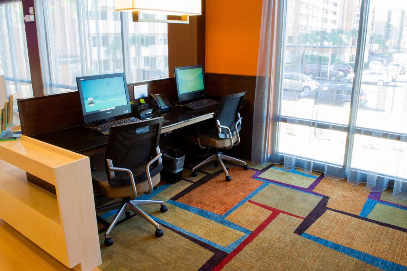 Two computer workstations with chairs in a Wavecrest Lodge hotel office near large windows.
