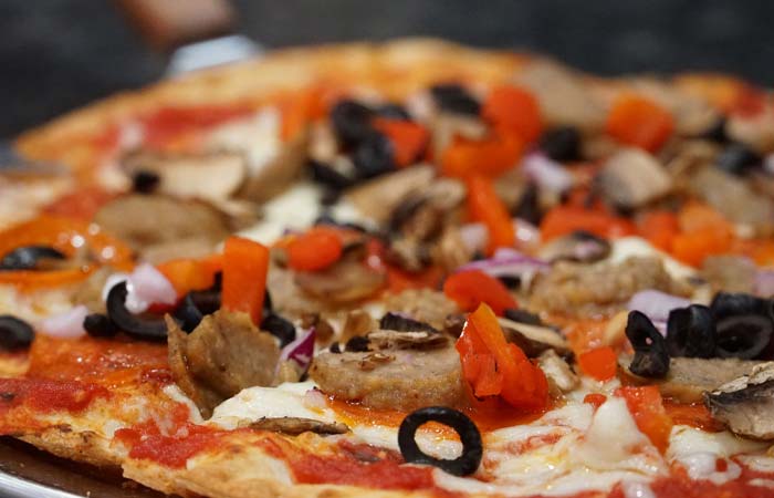 Close-up of pizza topped with mushrooms and sausage, perfect for enjoying at Wavecrest Lodge.