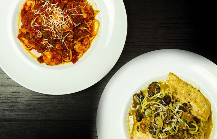 Two white plates at Wavecrest Lodge: pasta in red sauce, fish with mushrooms and vegetables.