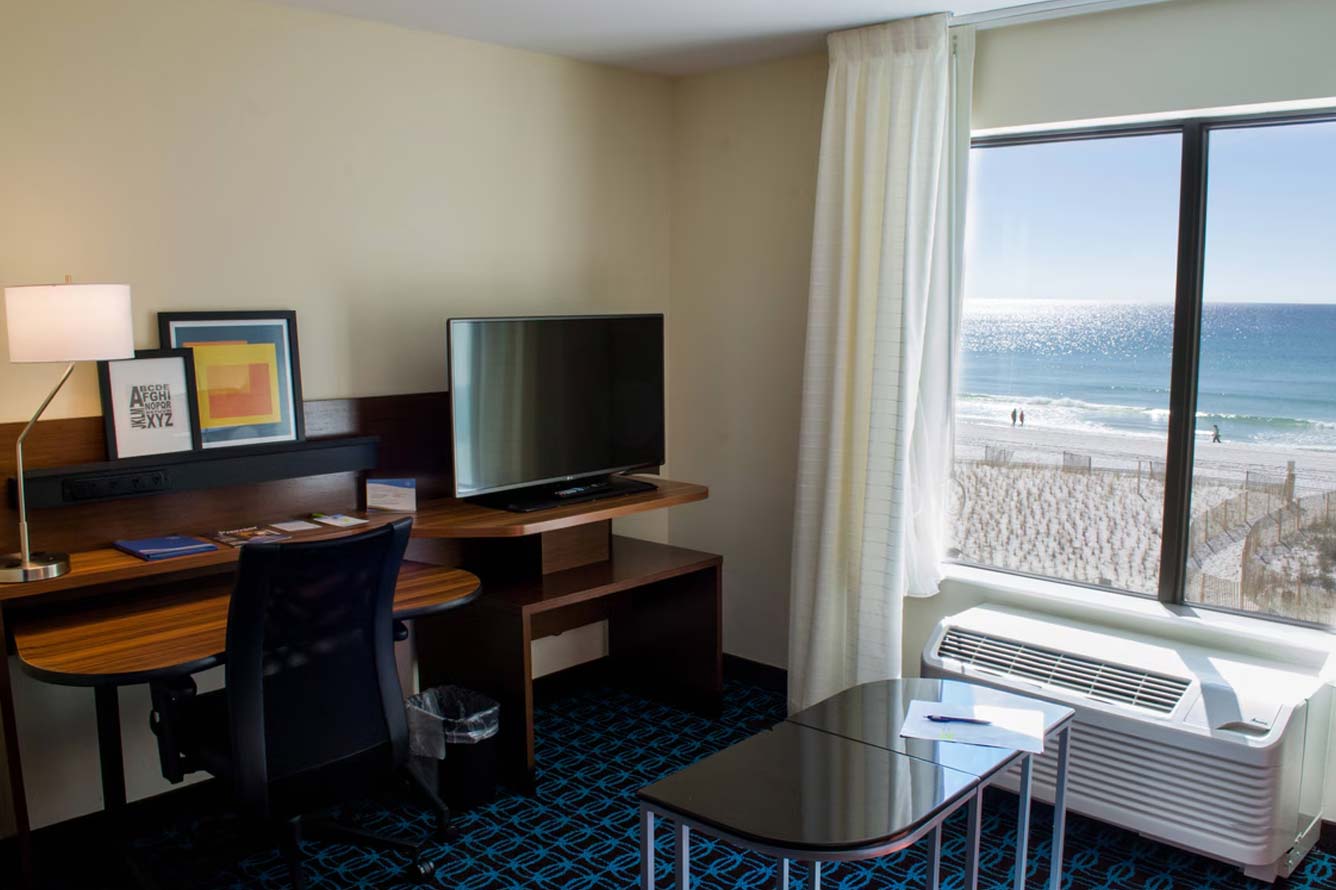 Hotel room with desk, TV, and ocean view at Wavecrest Lodge in Fort Walton Beach Hotel.