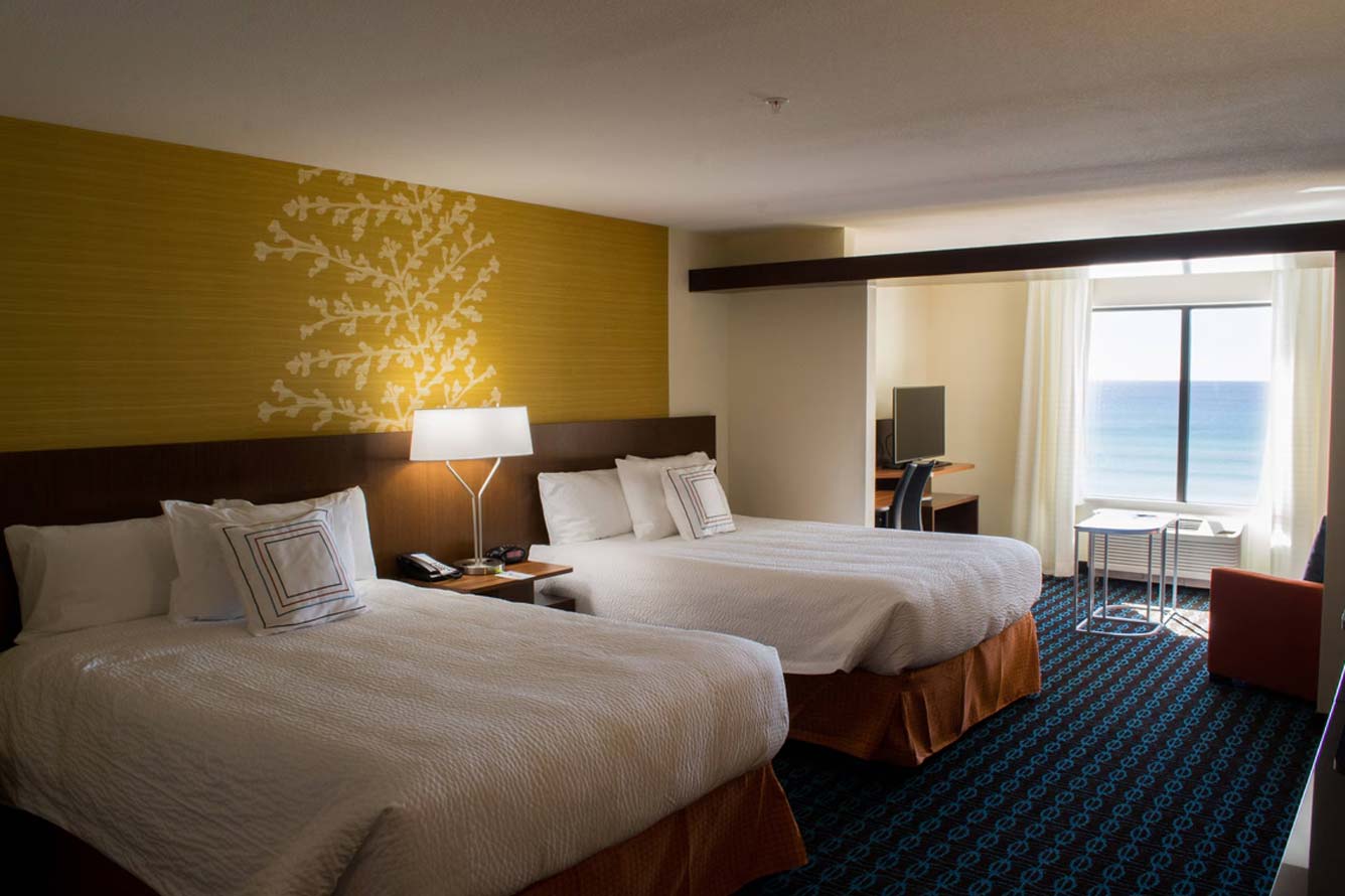 Wavecrest Lodge hotel room with two beds, desk, and ocean view at Fort Walton Beach Hotel.