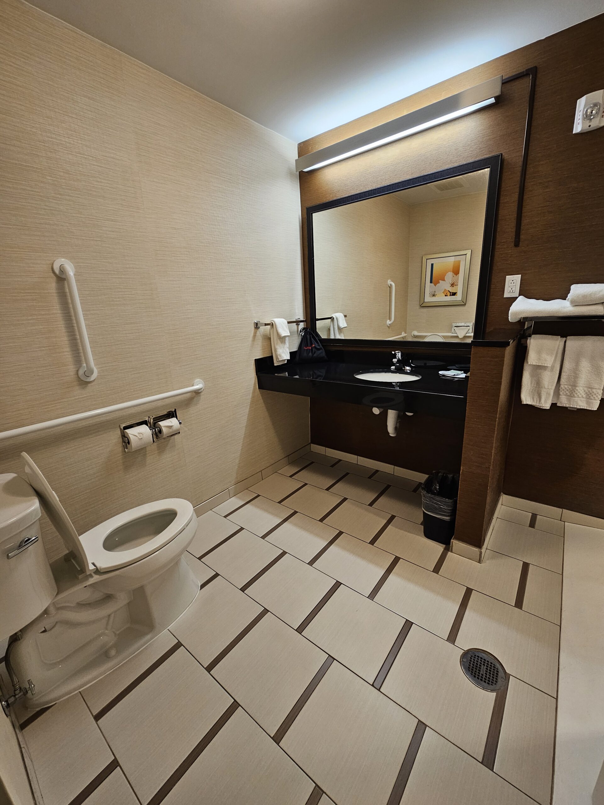 Accessible Wavecrest Lodge bathroom with grab bars, large sink, mirror, and tiled floor.