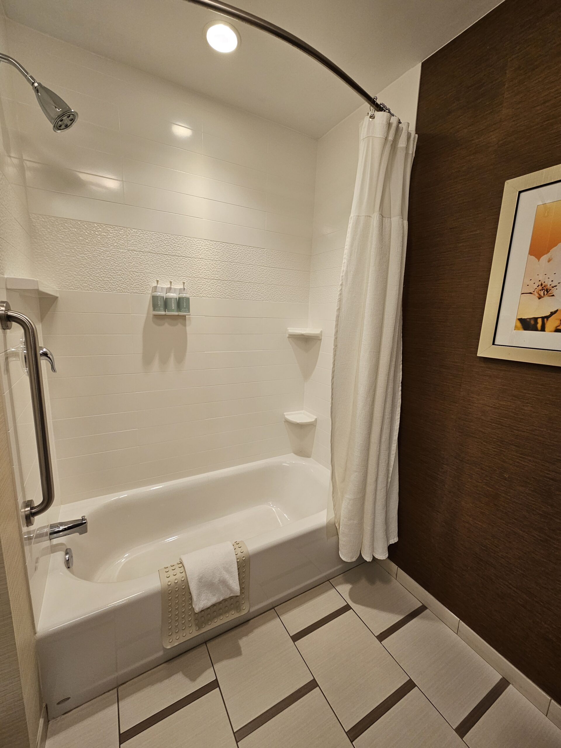 Modern bathroom at Wavecrest Lodge with a white bathtub, shower curtain, and stylish wall art.
