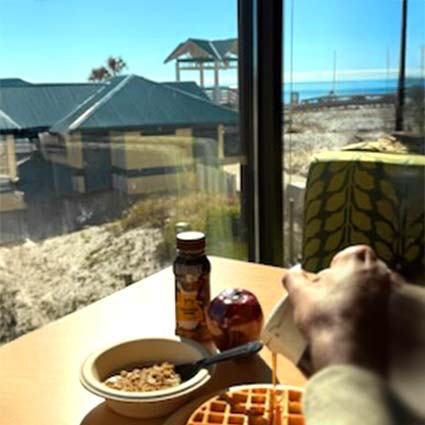 Guest drizzles syrup on a free fresh made continental breakfast waffle at Wavecrest Lodge Hotel in Fort Walton Beach Florida