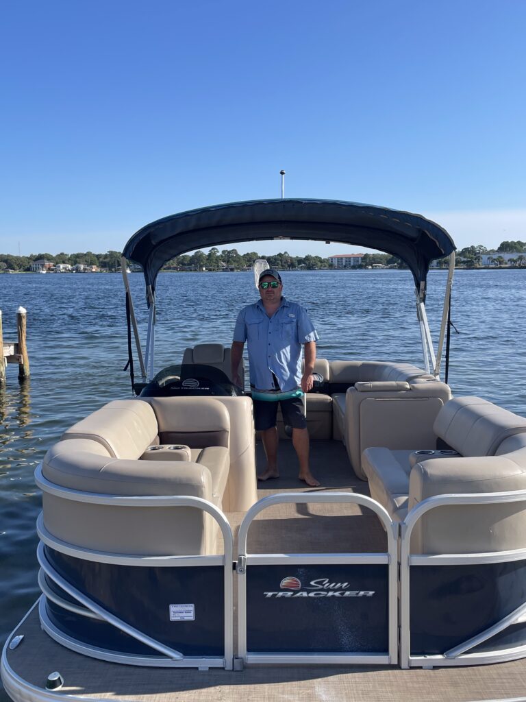 Captain from Destin Boat Company standing on a pontoon boat at the dock near Crab Island in Destin, Florida on the Emerald Coast.