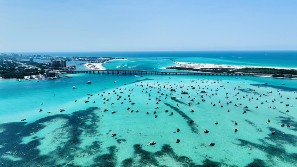 Aerial view of Crab Island near Destin and Okaloosa Island with boats gathered in clear emerald water along the Emerald Coast.