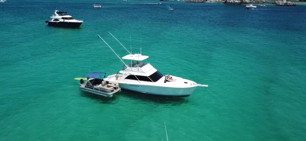 Pontoon boat and yacht anchored at Crab Island in Destin, Florida with clear emerald water on the Emerald Coast.