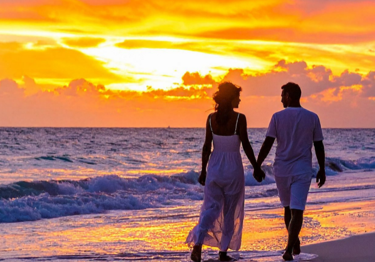 Couple walking along the beach at sunset on Okaloosa Island along the Gulf of America near Wavecrest Lodge