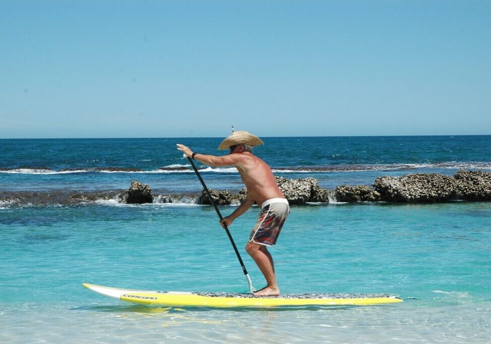 Woman stand up paddle boarding in clear emerald water on Okaloosa Island near Fort Walton Beach on Florida’s Emerald Coast.