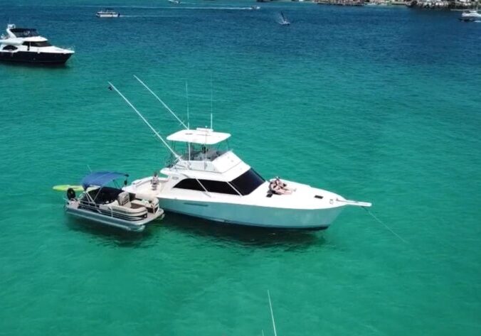 Pontoon boat and yacht anchored at Crab Island in Destin, Florida with clear emerald water on the Emerald Coast.